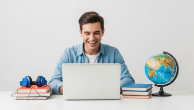 شخص يتعلم اللغة الإنجليزية بسعادة باستخدام حاسوب محمول مع كتب وسماعات رأس.